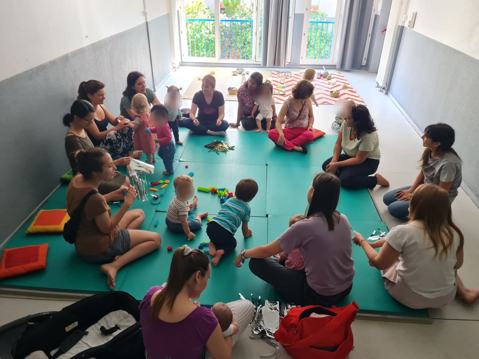Familles et tout-petits assis en cercle sur un grand tapis lors d’un atelier Élever en Tribu